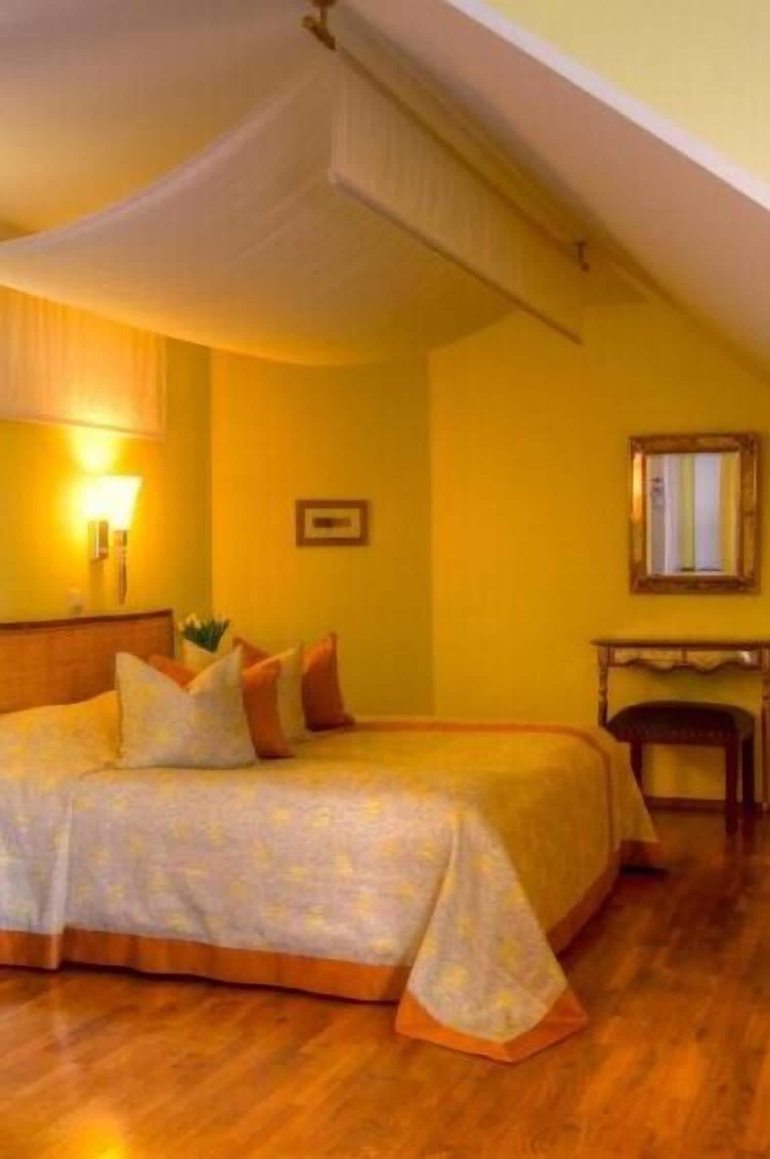 A hotel room with a bed, a nightstand, a lamp, and a mirror on the wall.
