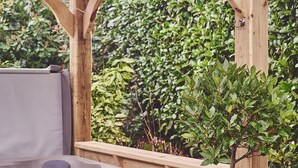 Een hottub onder een houten pergola, met een tuin op de achtergrond.