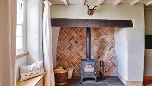 A cozy room with a fireplace, a bench with cushions, and a brick wall.