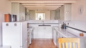 A kitchen with white cabinets, a wooden ceiling, and a window with a view.