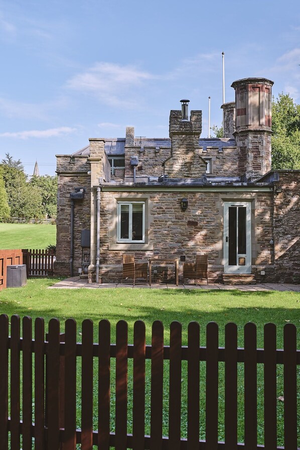 A stone building with a chimney, a door, and a window.