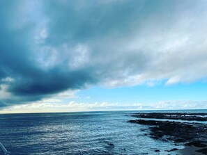 Paisatge costaner amb una riba rocosa i una vista de l'oceà sota un cel nuvolós.