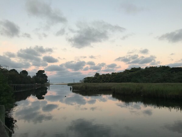 A calm river with a bridge in the distance, surrounded by trees and vegetation. - Vacation Mode (Lorne)