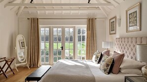 A bedroom with a large bed, a desk, a chair, and a view through a glass door. - Flock Cottage -  a cottage that sleeps 8 guests  in 4 bedrooms (Pudleston)