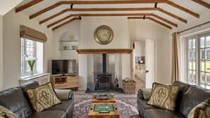 A living room with a fireplace, leather sofas, a wooden coffee table, and a television. - Flock Cottage -  a cottage that sleeps 8 guests  in 4 bedrooms (Pudleston)