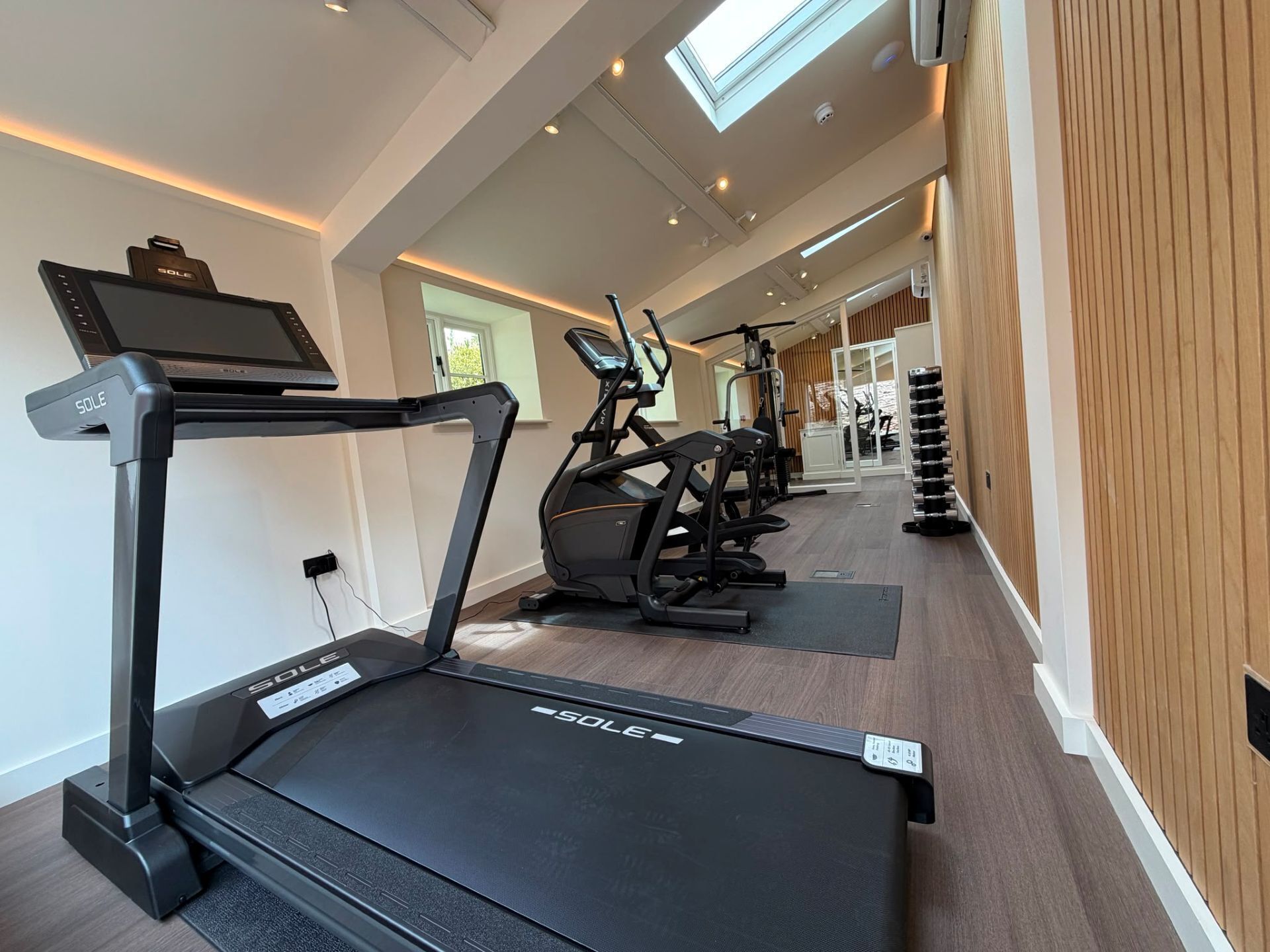 A modern gym with treadmills, stationary bikes, and a wall-mounted TV.