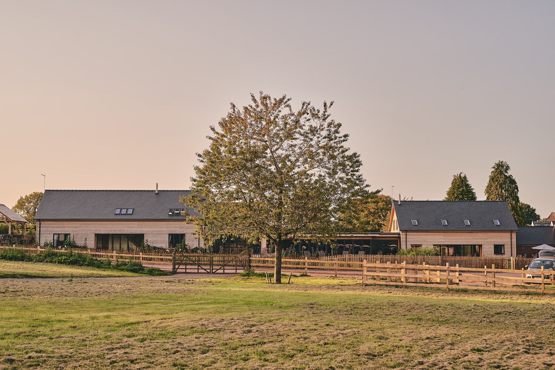 A modern building with a flat roof, large windows, and a wooden fence in front.