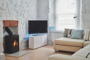 Relax in this inviting living room with a flat-screen TV, wood-burning stove, and comfortable sofa.