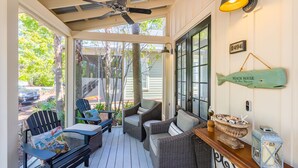A covered porch with wicker furniture, a ceiling fan, and a sign indicating the property is a beach house. - Screened Porch ~ Golf Cart ~ Community Pool (Miramar Beach)