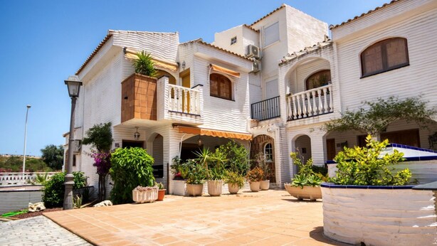 Un edificio blanco con varios balcones y un patio con plantas en macetas.