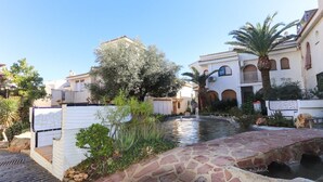 Un patio con fuente de agua, sendero de piedra y edificios tradicionales con ventanas y balcones de arco.