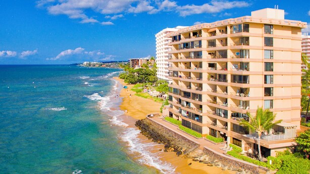 Ein Strandhotel mit mehreren Balkonen, einem Sandstrand und Meerblick.