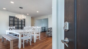 Un coin repas avec une table et des chaises en bois, un lustre et une porte en bois foncé.
