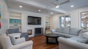 Un salon moderne doté d’une cheminée, d’un téléviseur à écran plat et d’un ventilateur de plafond.