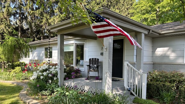 Une maison avec un porche, un drapeau et une boîte aux lettres.