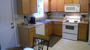 A kitchen with wooden cabinets, a white stove, a microwave, and a dishwasher. - Spacious Townhouse in the ❤ of Fayetteville (Fayetteville)