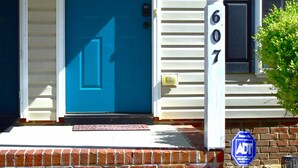 A blue door with a 'WELCOME' sign, a brick step leading to the entrance, and a 'Secured by ADT' sign. - Spacious Townhouse in the ❤ of Fayetteville (Fayetteville)