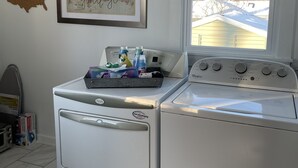 A laundry room with a washer and dryer, a map of the USA on the wall, and a window with a view of a house. - Cozy Cottage located near Czech Village and Newbo areas in Cedar Rapids, IA (Cedar Rapids)