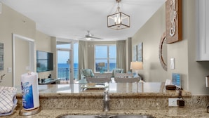 A modern kitchen with granite countertops, a stainless steel sink, and a ceiling fan.