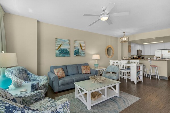 A living room with a sofa, coffee table, and chairs. There is a kitchen area with a refrigerator and microwave. - Unparalleled Second-Floor Luxury with Sweeping Gulf Views + Beach Chairs (Panama City Beach)