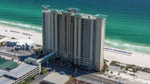 A high-rise hotel with multiple floors, a beachside location, and a parking area.