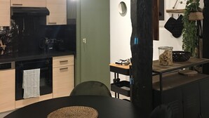 Une cuisine moderne avec un coin repas, comprenant une table à manger noire, une machine à café et un luminaire suspendu.