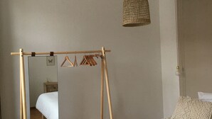 Une chambre à coucher comprenant un lit, une armoire en bois, un miroir et un luminaire suspendu.