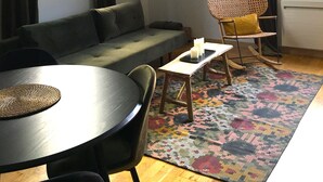 Un salon moderne avec un canapé, une table à manger, un tapis à motifs et un fauteuil.