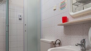 A bathroom with a glass-enclosed shower, a toilet, a sink, and a mirror.