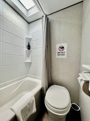 Un baño pequeño con bañera, inodoro y un perchero para toallas.