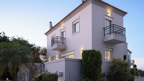 Un bâtiment à deux étages, doté d’un toit plat, d’un balcon au deuxième étage et d’un mur en pierre à l’avant.