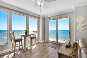 Enjoy ocean views from the spacious living area, featuring a sliding glass door to a balcony with a railing.