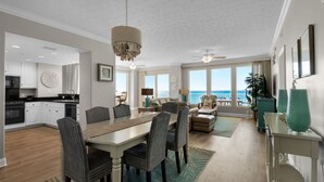 A spacious living area with a dining table, chairs, and a view of the ocean.