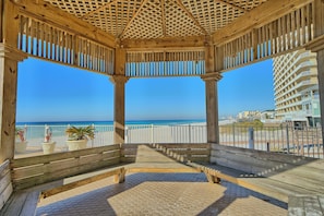 Relax in this serene beachside gazebo, featuring a bench for seating and a stunning view.