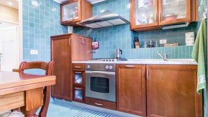 Een keuken met houten kastjes, een fornuis en een spoelbak.