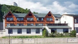 A row of modern houses with a sloped roof, large windows, and a stone wall in front. - Hoshito Midorino Romankan (Ogawa-mura)