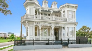 A white Victorian-style building with a balcony and ornate detailing.