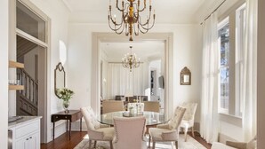 A dining room with a glass table surrounded by four chairs, a chandelier, and a large mirror on the wall.