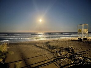 Une plage avec des vagues, une tour de surveillance des sauveteurs et un ciel dégagé.