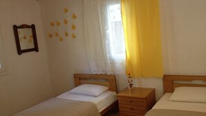 A bedroom with two single beds, a wooden nightstand with a lamp, a window with lace curtains, and butterfly wall decals. - Cottage House (Agios Gordios, Corfu)