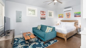 Un dormitorio moderno con cama, sofá, televisión y obras de arte en las paredes.