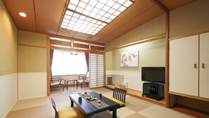 A traditional Japanese-style room with tatami flooring, a low table with cushions, a television, and sliding doors. -  Livemax Resort Izukogen ANNEX (Ito)