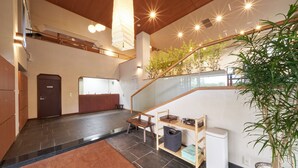 A spacious interior with a staircase, wooden flooring, a reception desk, a trash bin, and a potted plant. -  Livemax Resort Izukogen ANNEX (Ito)