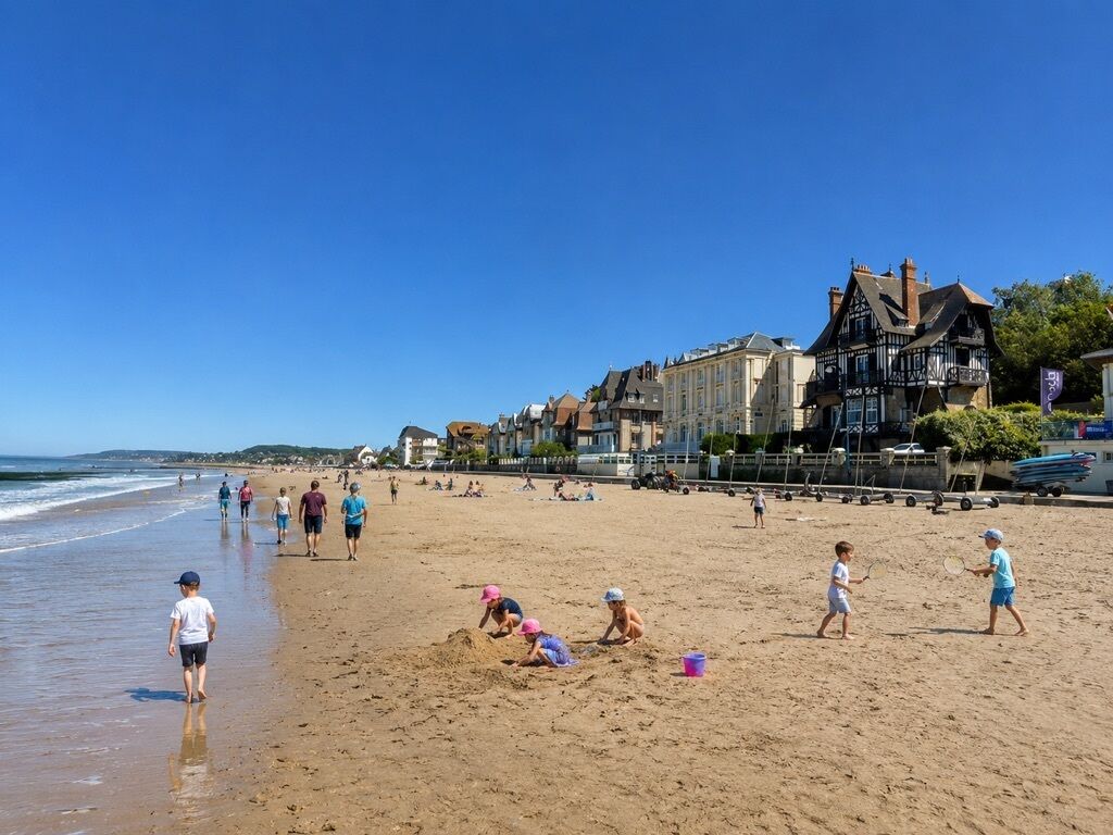 A beach with people walking and playing, buildings in the background, and a clear sky.