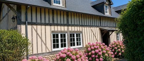 A traditional half-timbered house with a steeply pitched roof, a chimney, and a front entrance.