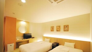 Une chambre d’hôtel avec deux lits, un bureau avec un ordinateur, une télévision et un miroir fixé au mur.