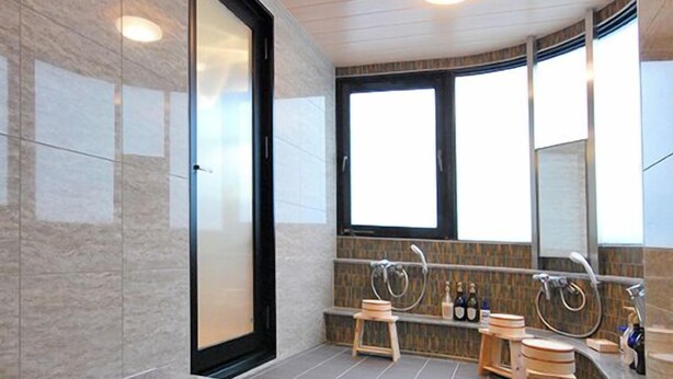 Une salle de bain moderne dotée d’une douche à parois de verre, d’un banc en bois, d’un grand miroir et d’une fenêtre laissant entrer la lumière naturelle.