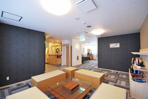 A hotel lobby with a reception desk, seating area, and a small kitchenette. - Park Hotel Pinza (Ichinomiya)