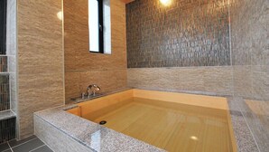 Une salle de bain moderne avec une grande baignoire, une fenêtre et un mur à texture.