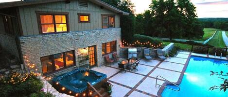 A two-story house with a swimming pool, outdoor seating, and string lights.